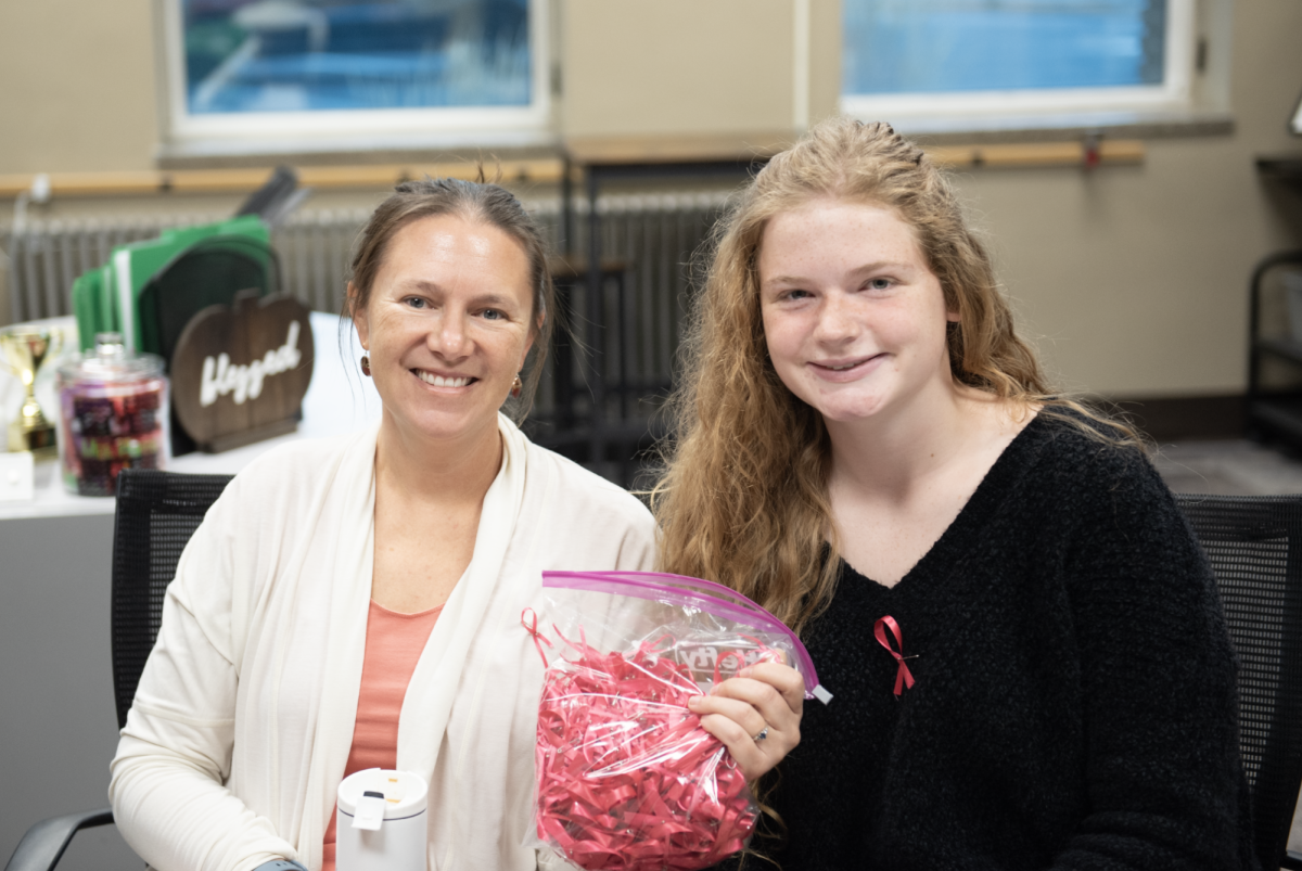 10.24.24 (From L to R) Teacher Krista Cunningham and Senior Annie Hanser collecting money in the office and handing out pink ribbons for Pink Day. 